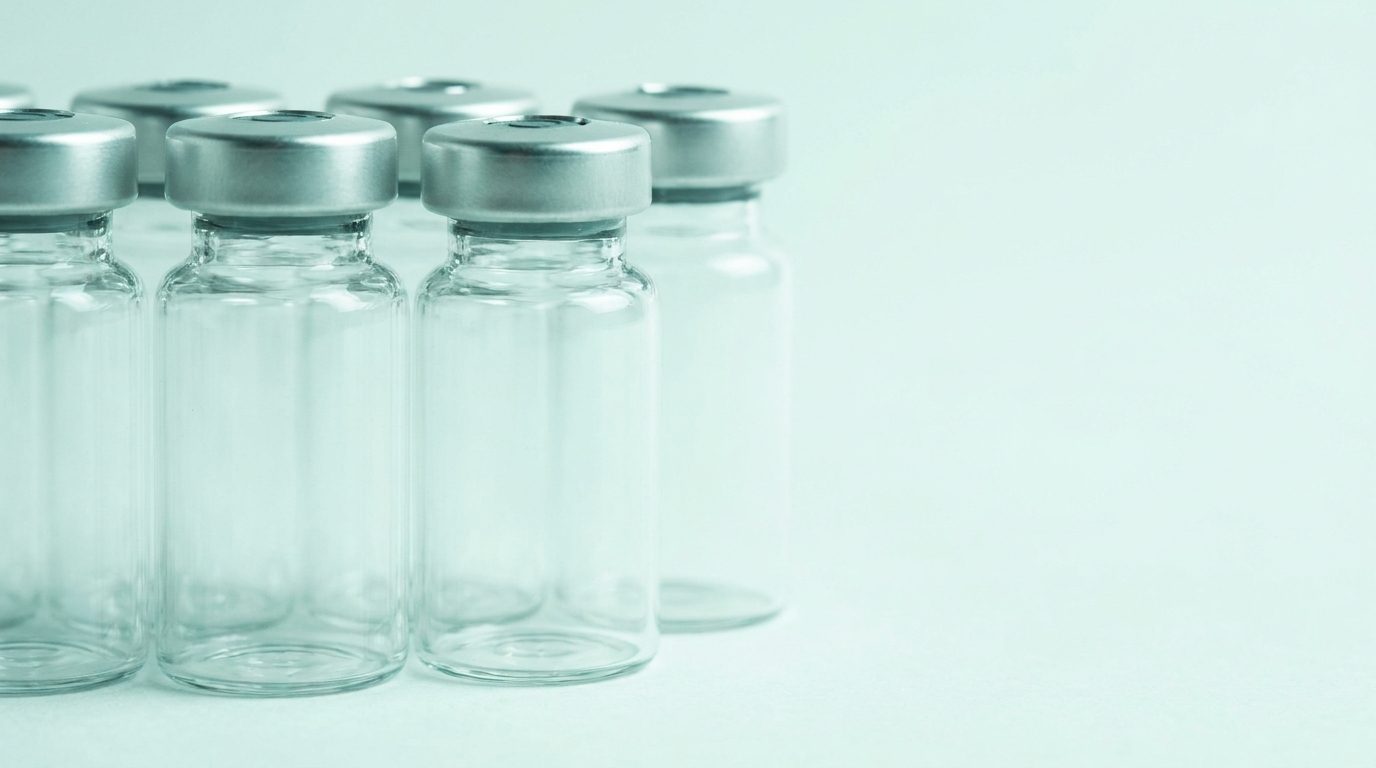 Empty laboratory vials with crimp caps on a pale surface.
